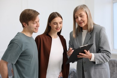 Photo of Smiling real estate agent working with couple at home