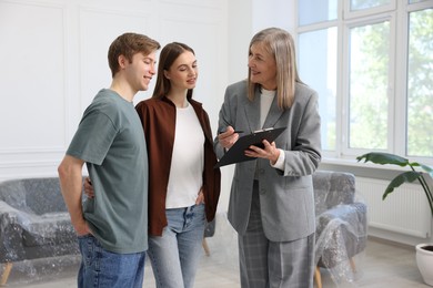 Photo of Smiling real estate agent working with couple at home