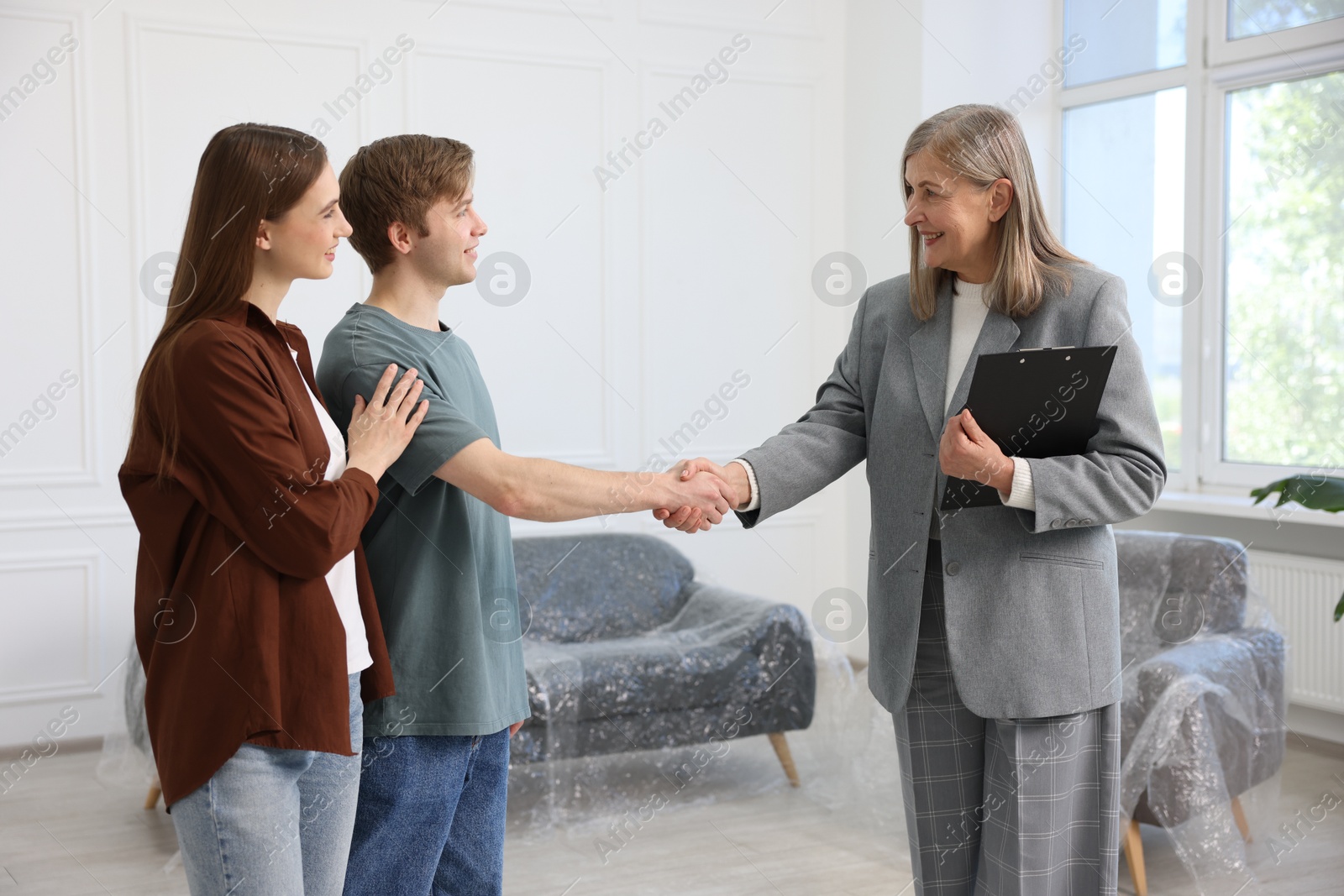 Smiling real estate agent shaking hands with new owner indoors Photo of Smiling real estate agent shaking hands with new owner indoors