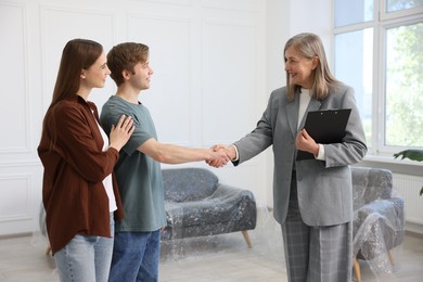 Photo of Smiling real estate agent shaking hands with new owner indoors