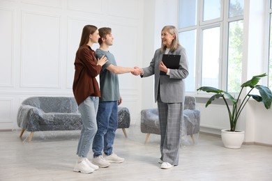 Photo of Smiling real estate agent shaking hands with new owner indoors