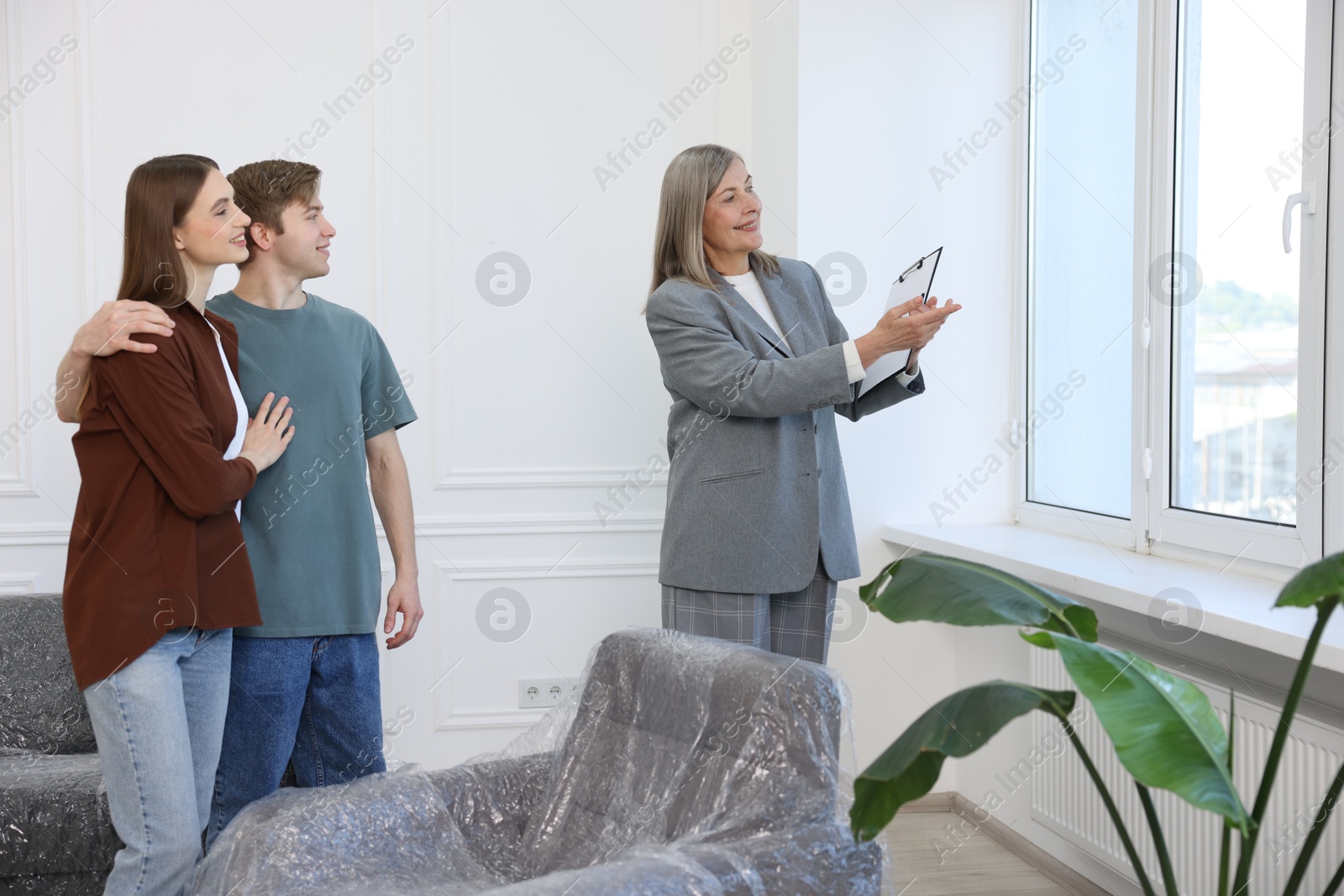 Smiling real estate agent showing apartment to couple indoors Photo of Smiling real estate agent showing apartment to couple indoors