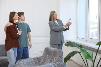 Photo of Smiling real estate agent showing apartment to couple indoors