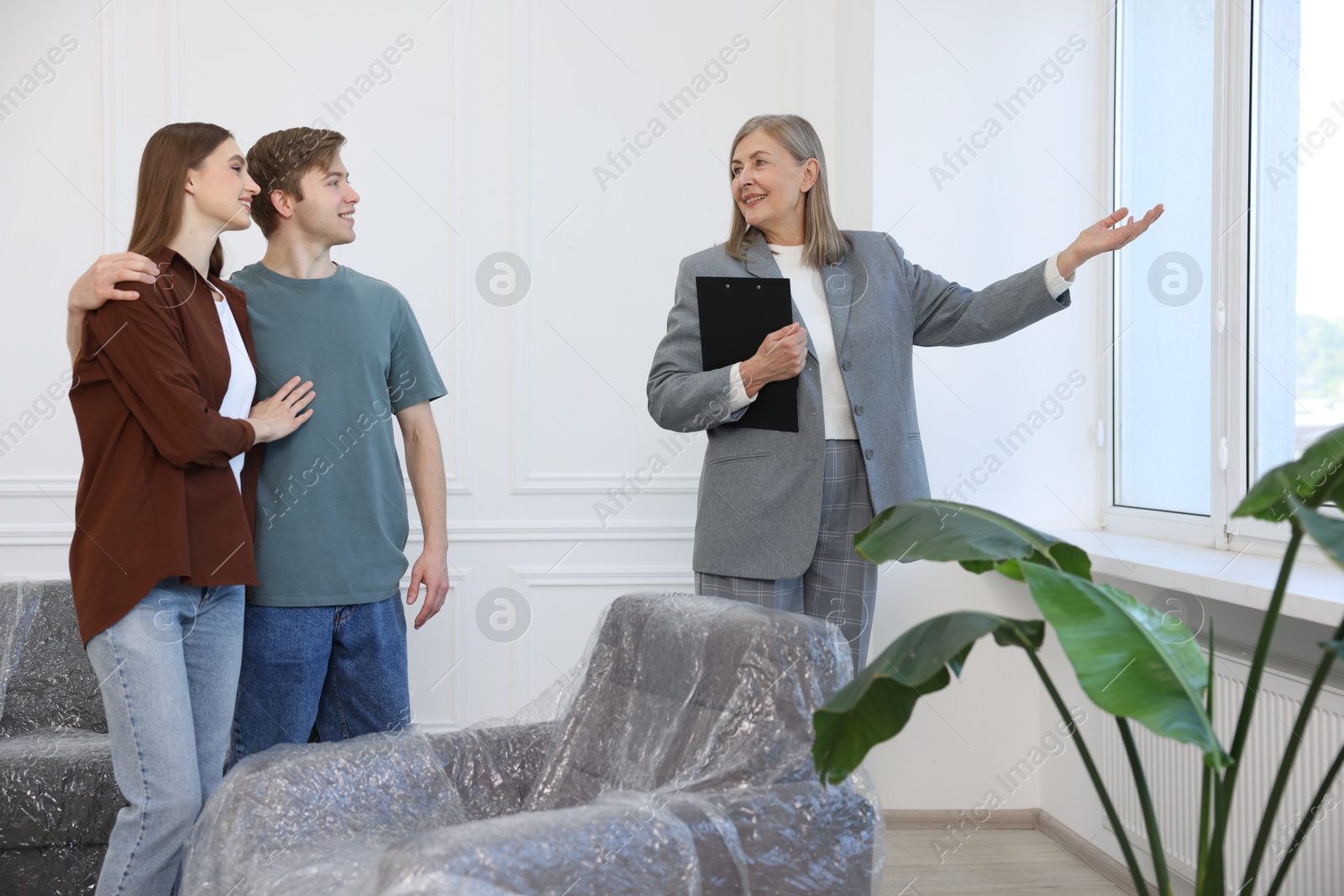 Smiling real estate agent showing apartment to couple indoors Photo of Smiling real estate agent showing apartment to couple indoors
