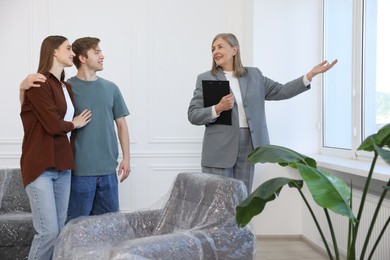 Photo of Smiling real estate agent showing apartment to couple indoors