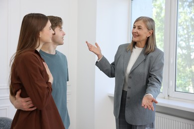 Photo of Smiling real estate agent working with couple at home