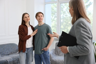 Photo of Real estate agent and young couple at home, selective focus