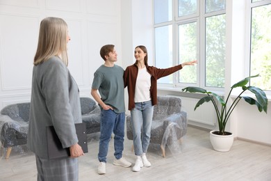 Photo of Real estate agent and young couple at home