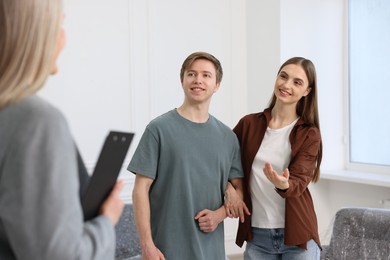 Photo of Real estate agent and young couple at home, selective focus