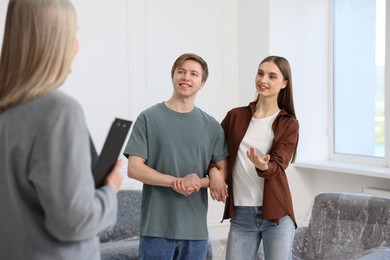 Photo of Real estate agent and young couple at home, selective focus