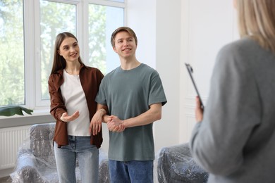 Photo of Real estate agent and young couple at home, selective focus