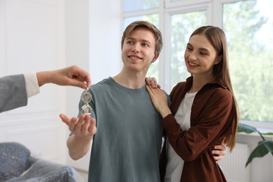 Photo of Real estate agent giving house key to new owner indoors, closeup
