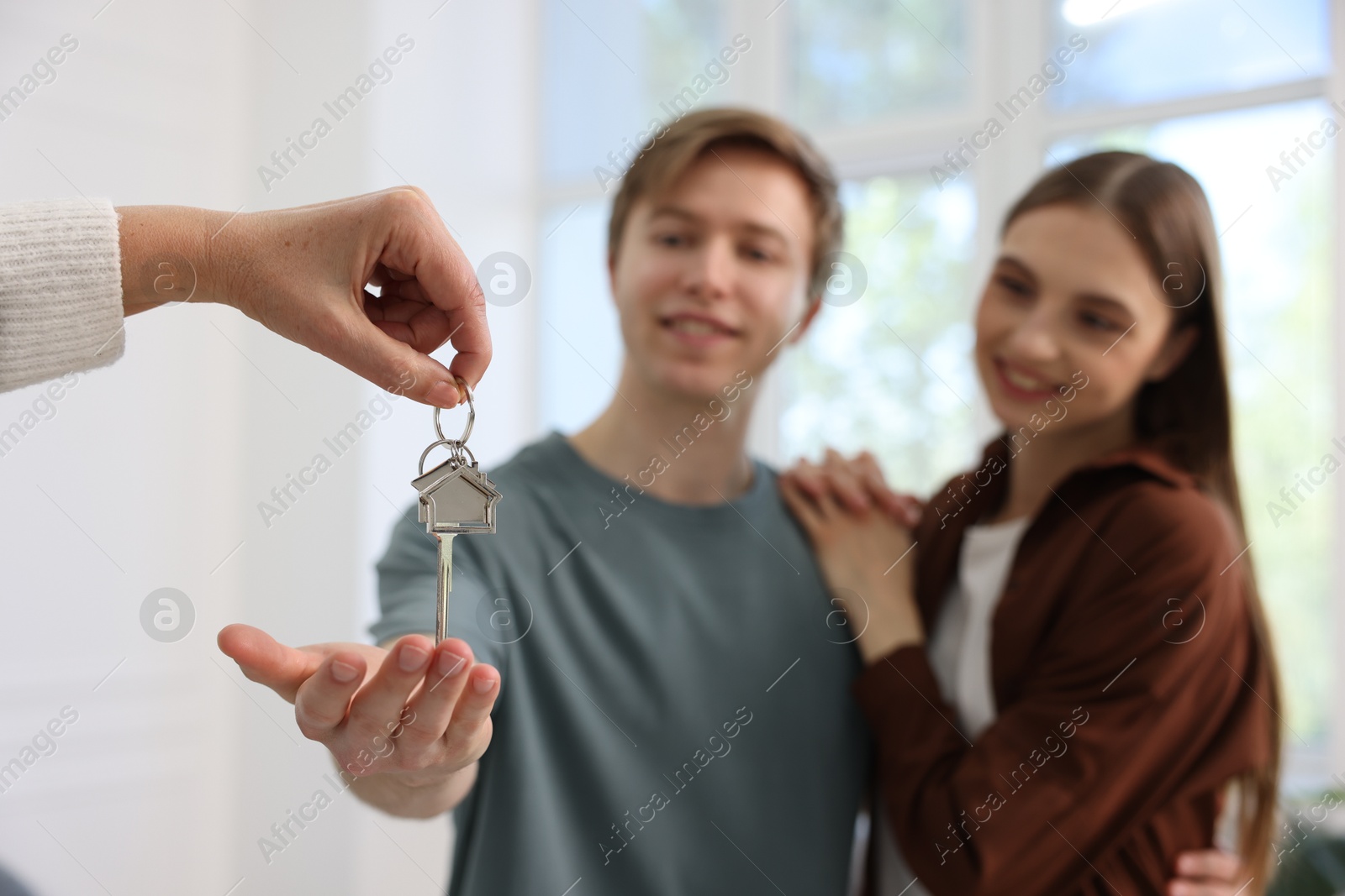 Real estate agent giving house key to new owner indoors, selective focus Photo of Real estate agent giving house key to new owner indoors, selective focus