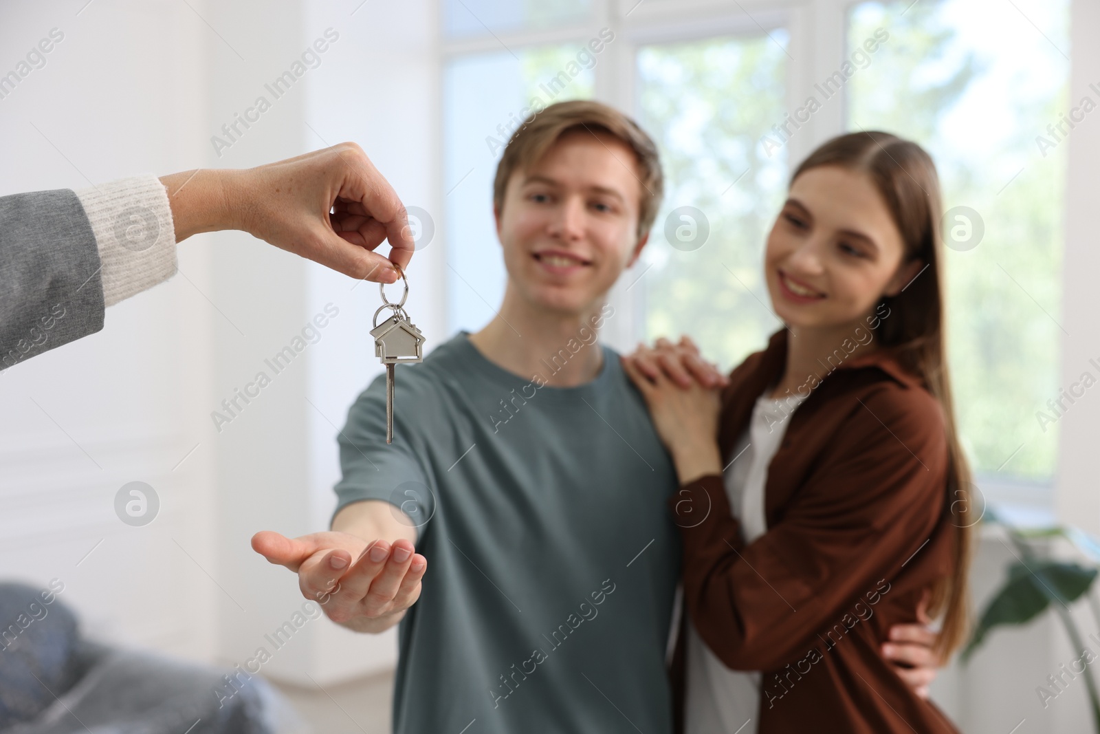 Real estate agent giving house key to new owner indoors, selective focus Photo of Real estate agent giving house key to new owner indoors, selective focus