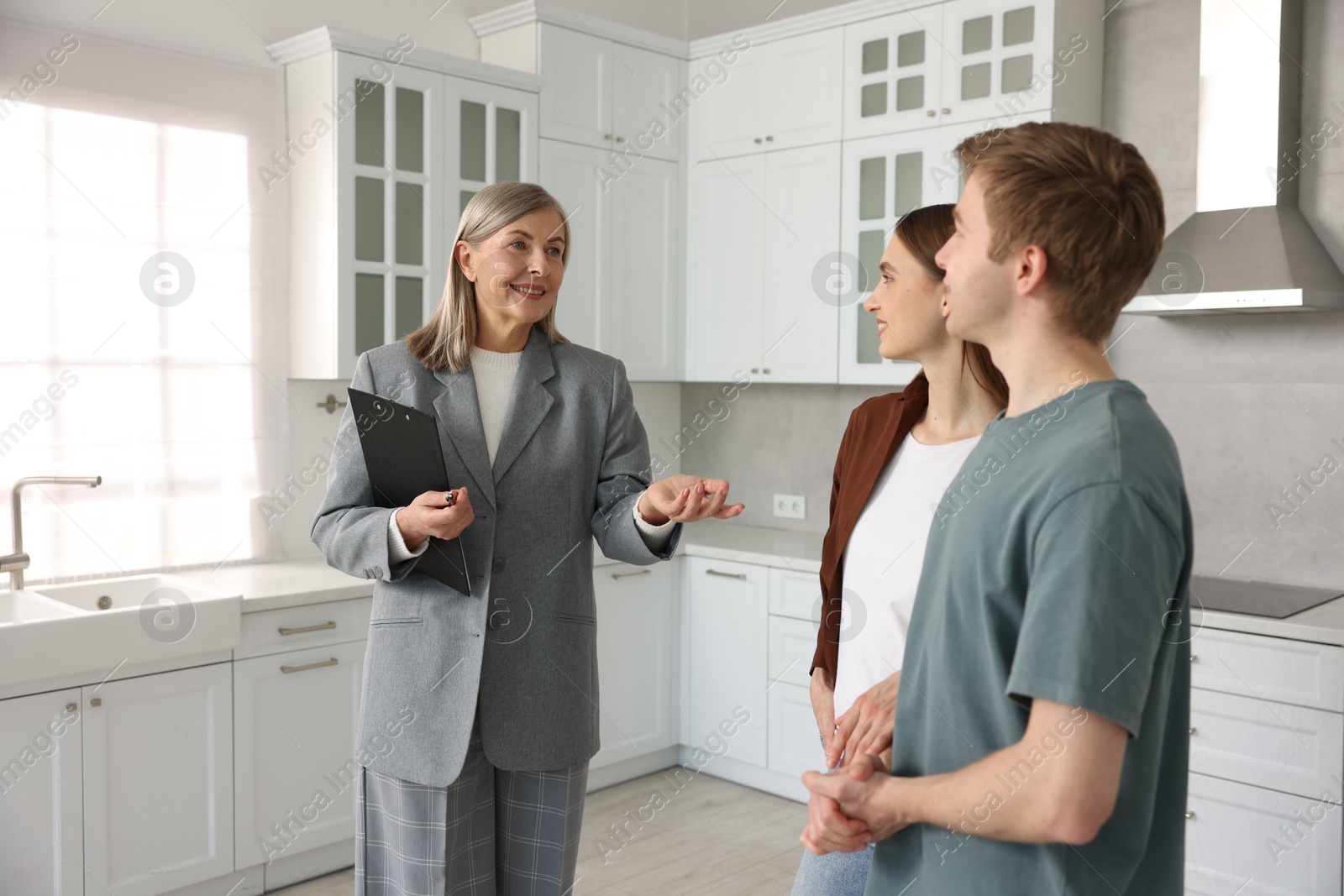 Smiling real estate agent with tablet working with couple in kitchen Photo of Smiling real estate agent with tablet working with couple in kitchen