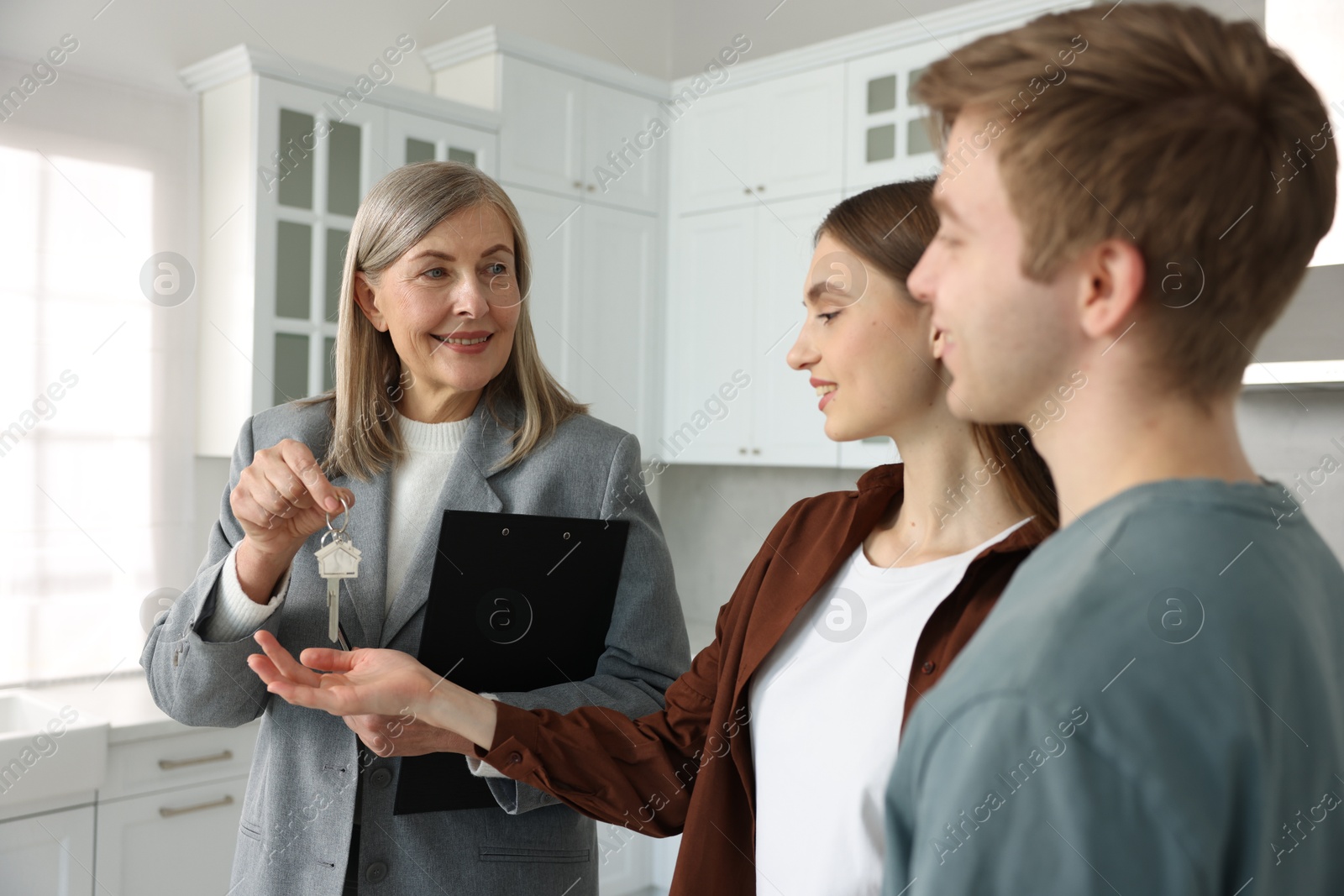 Smiling real estate agent giving house key to new owner in kitchen Photo of Smiling real estate agent giving house key to new owner in kitchen