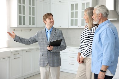 Photo of Smiling real estate agent working with couple in kitchen