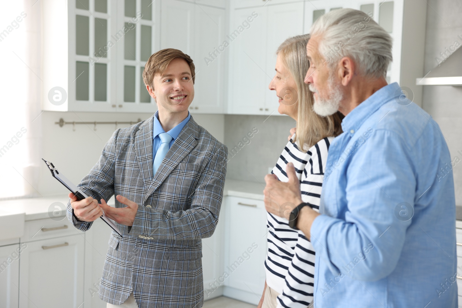 Smiling real estate agent working with couple in kitchen Photo of Smiling real estate agent working with couple in kitchen