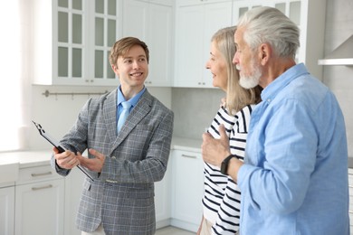 Photo of Smiling real estate agent working with couple in kitchen