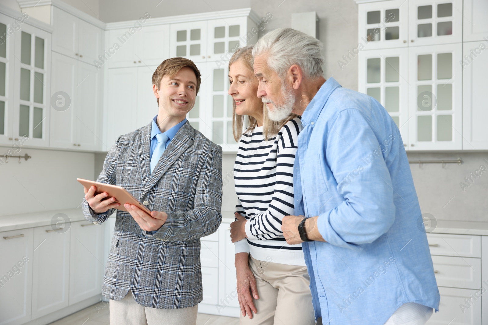 Smiling real estate agent with tablet working with couple in kitchen Photo of Smiling real estate agent with tablet working with couple in kitchen