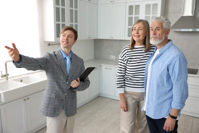 Photo of Smiling real estate agent showing apartment to couple indoors