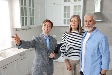 Photo of Smiling real estate agent showing apartment to couple indoors