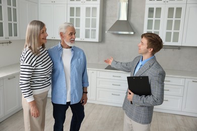 Photo of Smiling real estate agent showing apartment to couple indoors