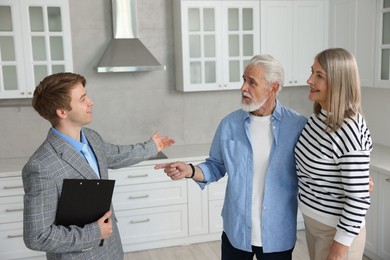 Photo of Smiling real estate agent working with couple in kitchen