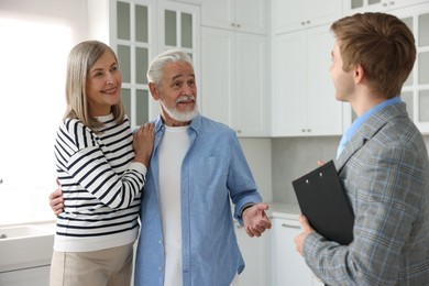 Photo of Real estate agent with clipboard working with couple in kitchen
