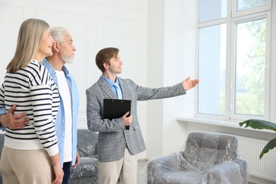 Photo of Smiling real estate agent showing apartment to couple indoors