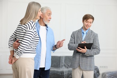 Photo of Smiling real estate agent with clipboard working with couple at home