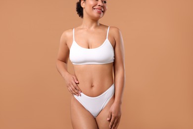 Photo of Woman in white underwear with smooth skin after epilation procedure on beige background, closeup