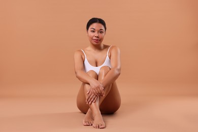 Photo of Woman in white underwear with smooth skin after epilation procedure on beige background