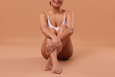 Photo of Woman in white underwear with smooth skin after epilation procedure on beige background, closeup