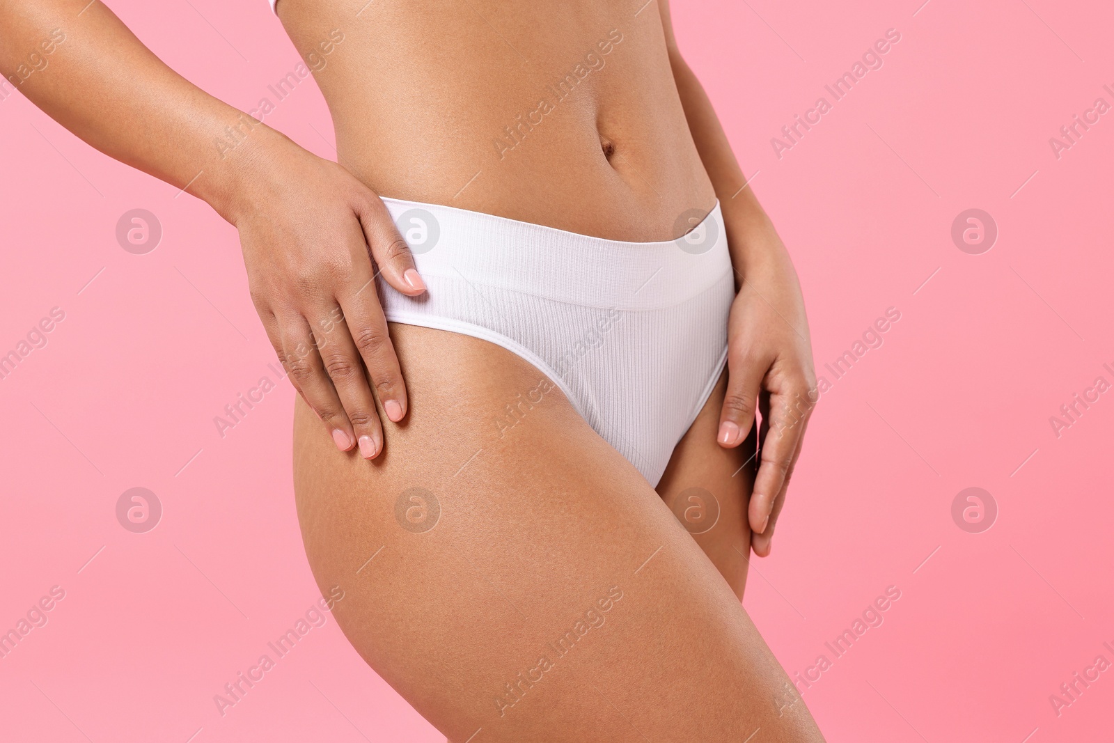 Woman in white underwear with smooth skin after epilation procedure on pink background, closeup Photo of Woman in white underwear with smooth skin after epilation procedure on pink background, closeup