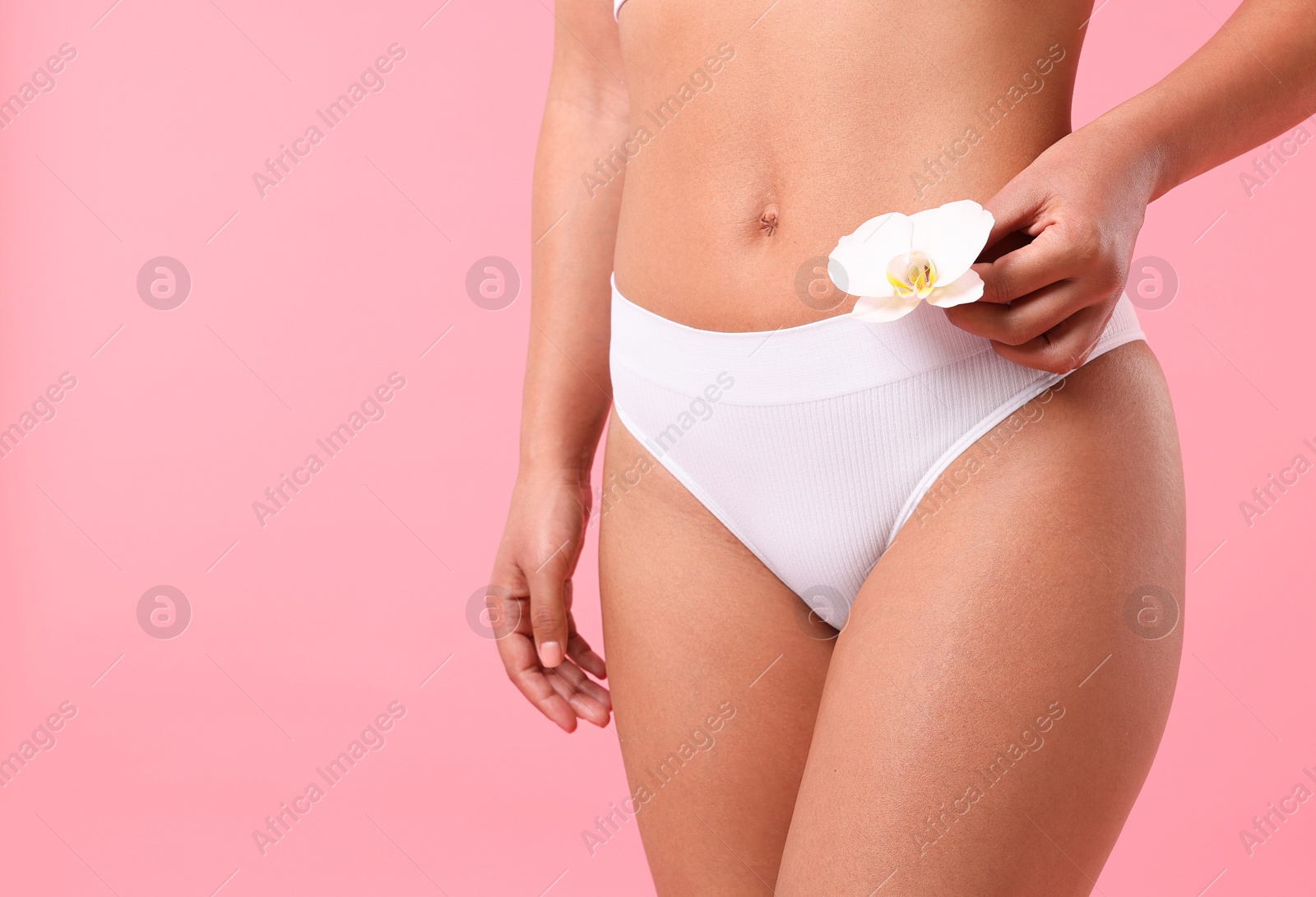 Woman in underwear with flower showing smooth skin after epilation procedure on pink background, closeup. Space for text Photo of Woman in underwear with flower showing smooth skin after epilation procedure on pink background, closeup. Space for text