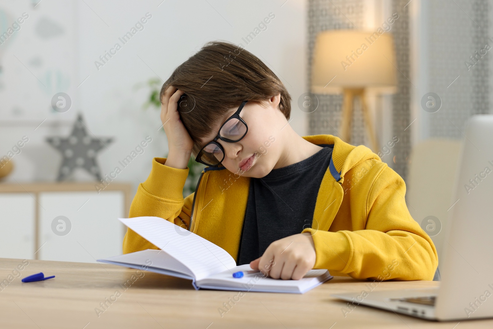 Cute little boy doing homework at table indoors Photo of Cute little boy doing homework at table indoors