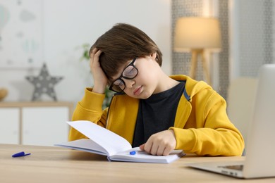 Photo of Cute little boy doing homework at table indoors