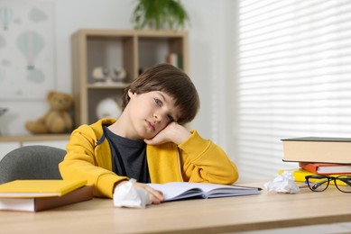 Photo of Cute little boy doing homework at table indoors