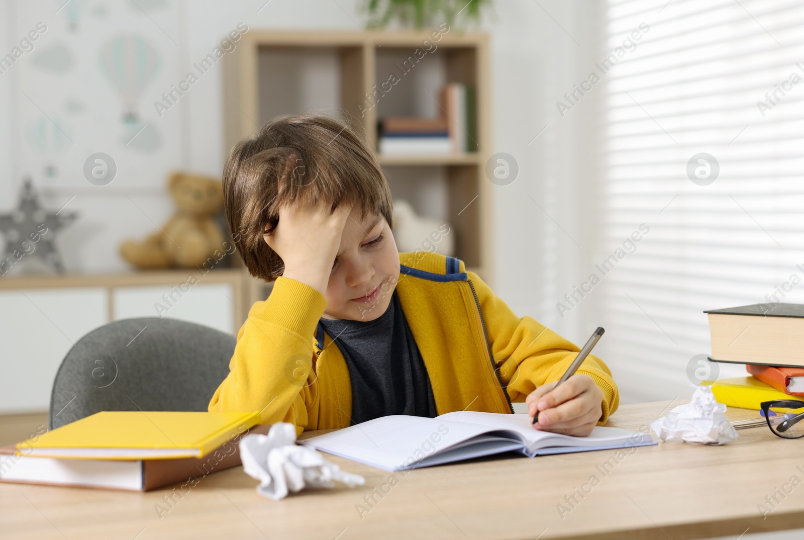 Tired little boy doing homework at table indoors Photo of Tired little boy doing homework at table indoors