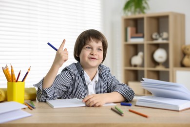 Photo of Cute little boy doing homework at table indoors