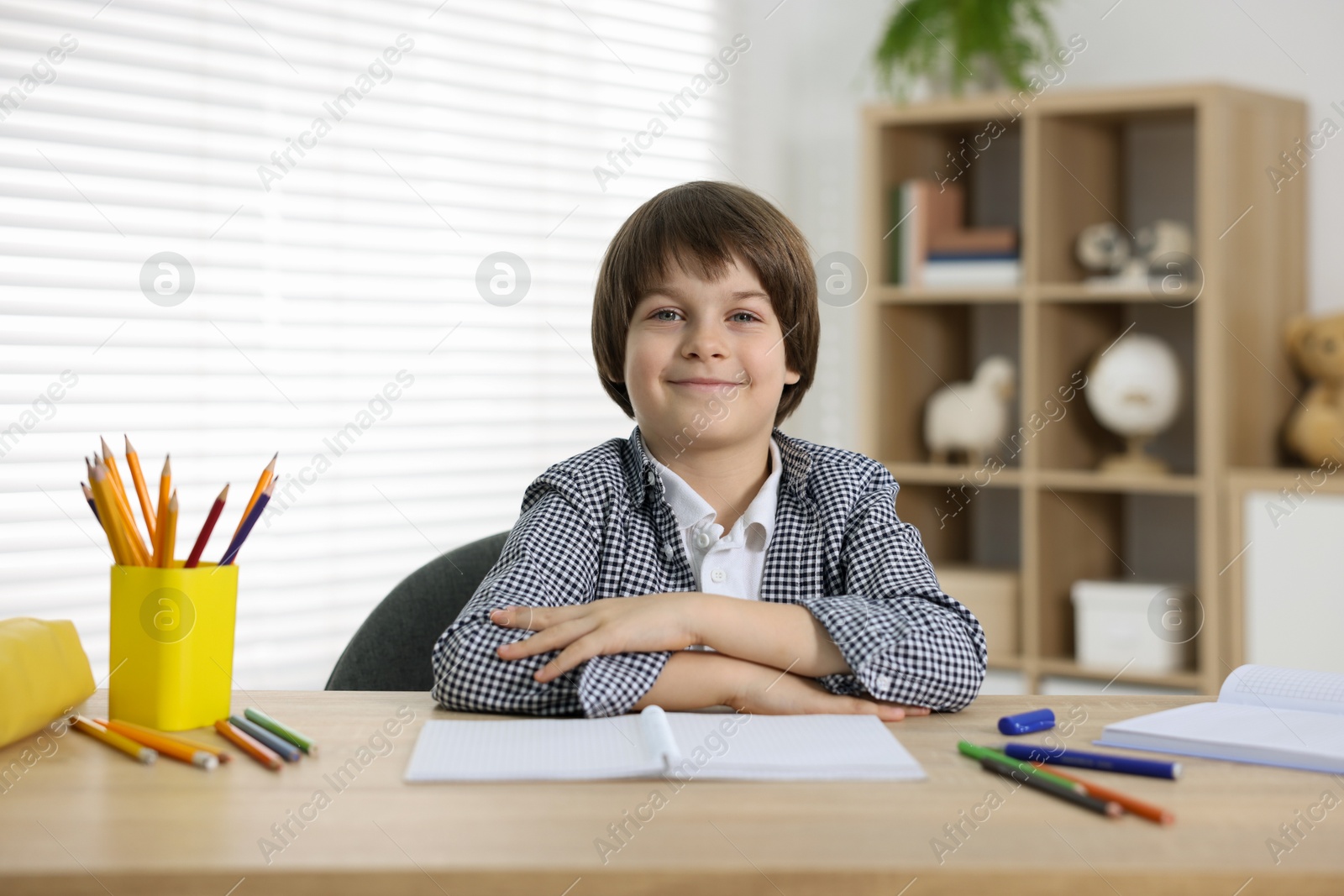 Cute little boy doing homework at table indoors Photo of Cute little boy doing homework at table indoors