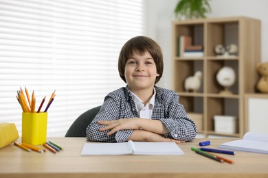 Photo of Cute little boy doing homework at table indoors