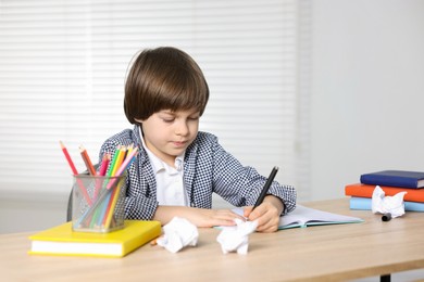 Photo of Cute little boy doing homework at table indoors