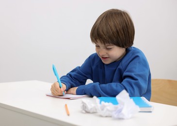 Photo of Cute little boy doing homework at desk indoors