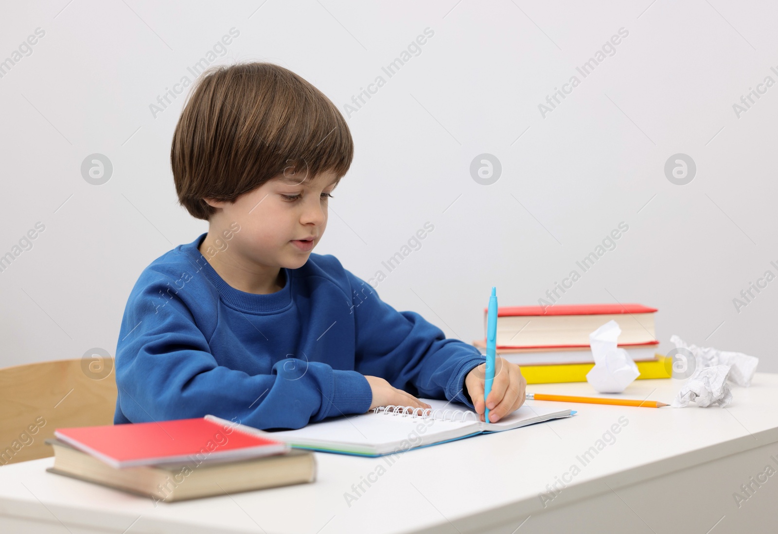 Cute little boy doing homework at desk indoors Photo of Cute little boy doing homework at desk indoors
