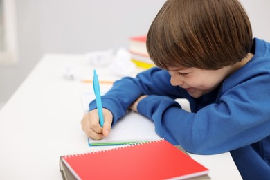Photo of Cute little boy doing homework at table indoors
