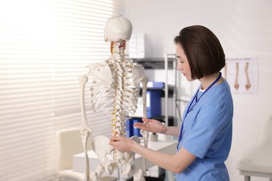 Photo of Doctor pointing at parts of human skeleton model in clinic