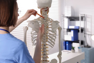 Photo of Doctor pointing at parts of human skeleton model in clinic