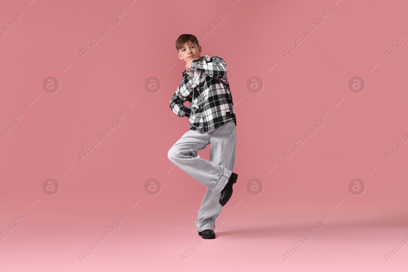 Boy with headphones in stylish clothes dancing on pink background Photo of Boy with headphones in stylish clothes dancing on pink background